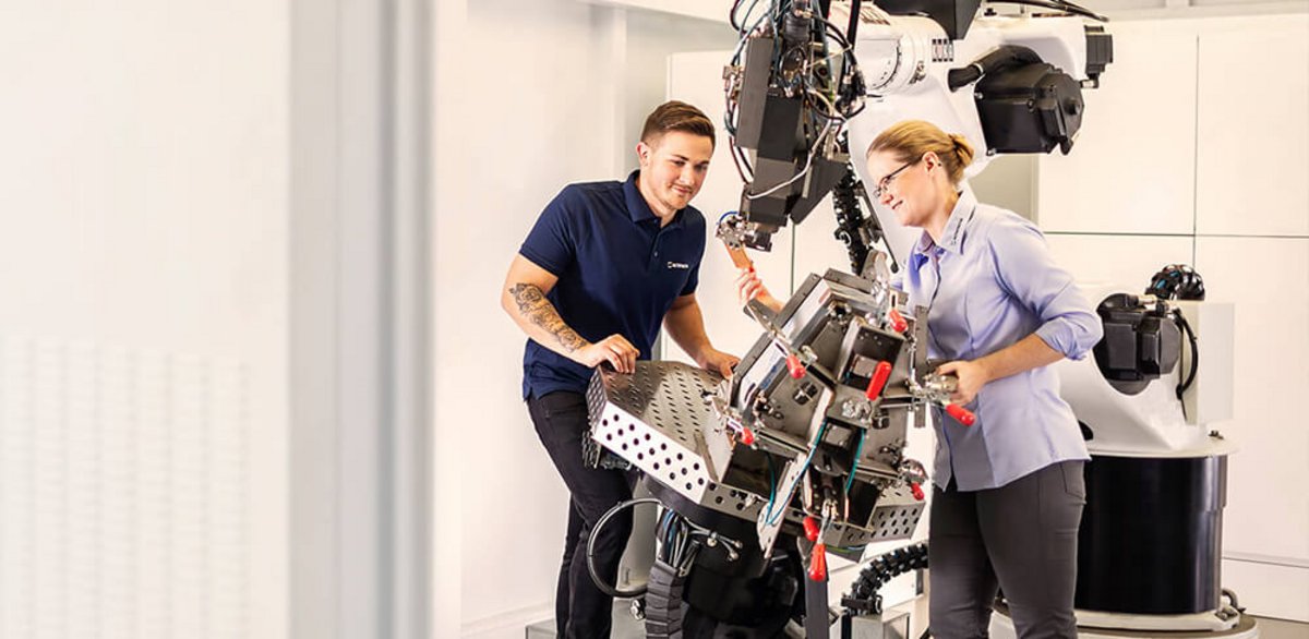 zwei Mitarbeiter an Roboter